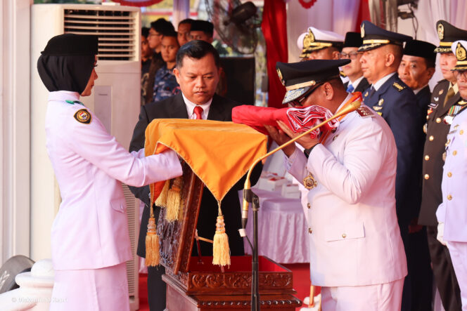 
					Wakil Gubernur Kepri, Nyanyang Haris Pratamura mencium bendera merah putih yang diserahkan Nurjihan Dwi Hanifah, Paskibraka yang bertugas membawa baki pada Upacara Penurunan Bendera Peringatan HUT ke-81 di Gedung Daerah, Tanjungpinang, Senin (17/8/2026).